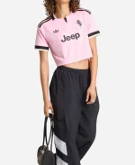 Lifestyle image of a model wearing the Adidas Juventus 26/27 Womens Away Cropped Soccer Shirt in true pink with black athletic pants for a modern sporty look.