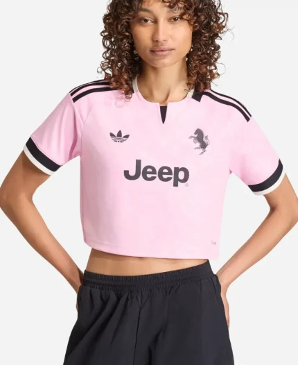 Portrait view of a model wearing the Adidas Juventus 26/27 Womens Away Cropped Soccer Shirt featuring true pink polyester fabric, Juventus crest, Adidas logo, and cropped fit.