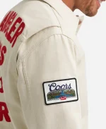 Close-up of woven rectangular Coors Banquet logo patch on the right sleeve of white cotton jacket.