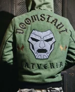 Lifestyle back view of a person wearing the Marvel Doctor Doom Army Hooded Varsity Jacket displaying the embroidered Doctor Doom artwork and Latveria graphics.