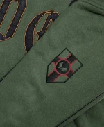Close-up sleeve detail of the Marvel Doctor Doom Army Hooded Varsity Jacket showing the embroidered arm patch on dark green fleece.