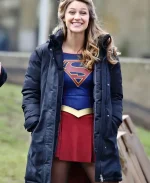 Melissa Benoist as Kara Danvers smiling in blue puffer coat on the Supergirl set