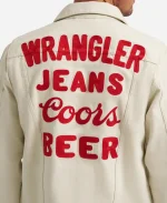 Close-up detail of textured red embroidered text Wrangler Jeans Coors Beer on white cotton fabric.